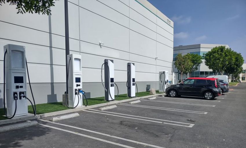 Sähköautojen latauspisteitä parkikapaikalla rakennuksen seinustalla.