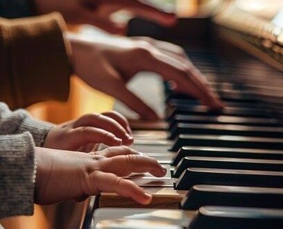 Aikuisen ja lapsen kädet soittavat pianoa lämpimässä sisätilassa
