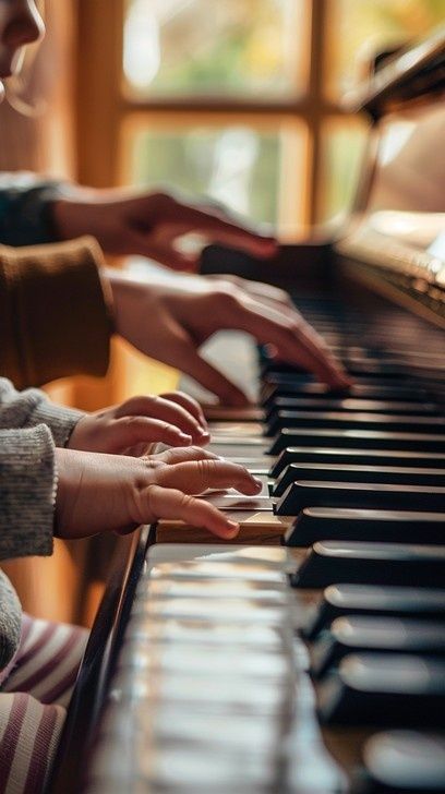 Aikuisen ja lapsen kädet soittavat pianoa lämpimässä sisätilassa