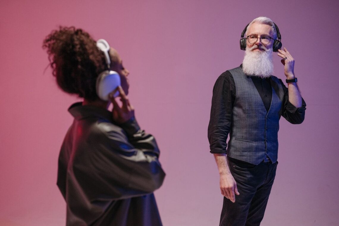 Kaksi henkilöä kuuntelee musiikkia kuulokkeilla violetissa tilassa