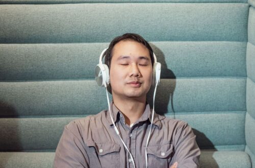 Silmät sulkenut mies kuuntelee musiikkia valkoisilla kuulokkeilla
